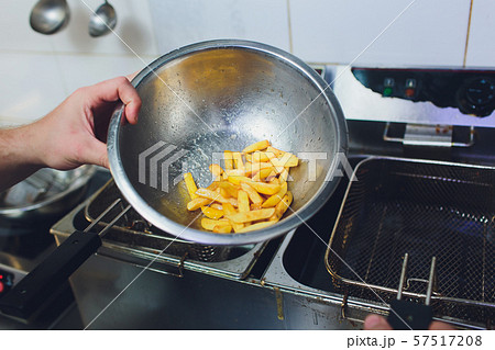 Female chef preparing french fries in kitchen. Female chef preparing french fries in kitchen. 57517208