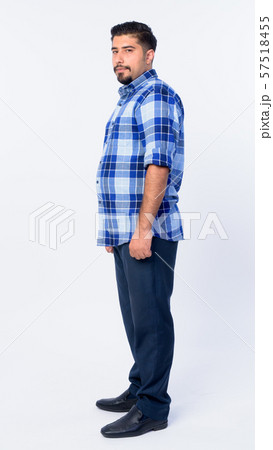 Full body shot profile view of bearded Persian hipster man looking at camera Full body shot profile view of bearded Persian hipster man looking at camera 57518455