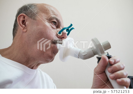 Senior hispanic man man testing breathing function by spirometry 57521253