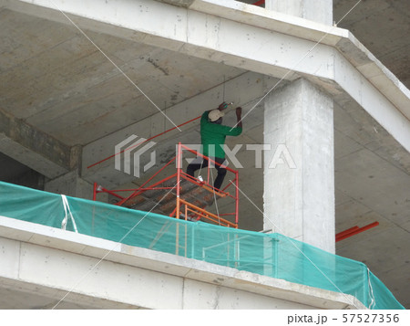 Construction workers working at height at the construction site. Using scaffolding as the temporary platform to work.  57527356