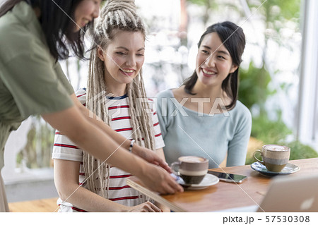 カフェの店員からおもてなしを受けて笑顔になる外国人と日本の友達の写真素材