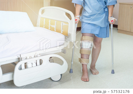 Asian woman patient with knee brace with walking stick in hospital ward after ligament surgery. 57532176