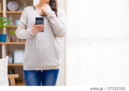 スマホを見て悩む女性 57532181