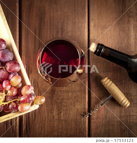 Wine Tasting. A photo of a red wine glass with a bottle, grapes, and a vintage corkscew, overhead 57533123