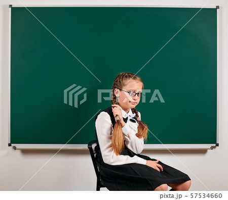 Portrait of a schoolgirl sitting near blackboard 57534660