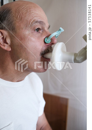 Senior hispanic man man testing breathing function by spirometry 57538141