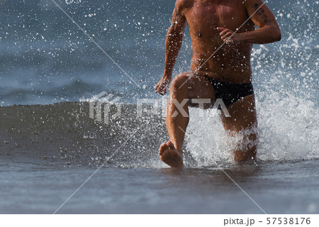Swimmer running out of ocean finishing swim race.Fit man ending swimming sprinting determined out of water 57538176
