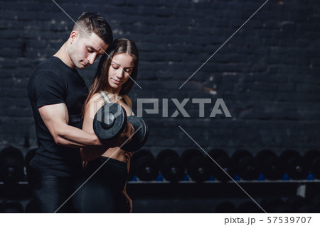 Two young guys and girls are engaged in the gym. During this time, they embraced themselves holding 57539707