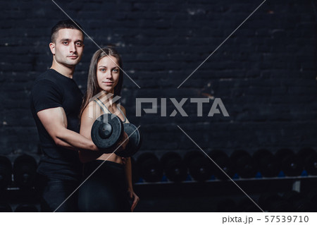 Two young guys and girls are engaged in the gym. During this time, they embraced themselves holding 57539710
