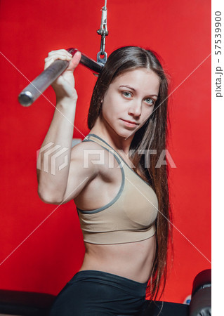 Beautiful young girl engaged in fitness in the gym. Brunette performs exercises on the simulator. 57539900