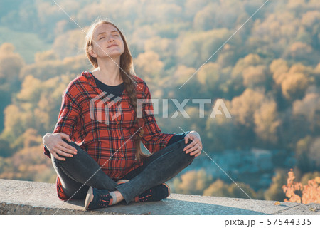 Pregnant woman sits on a hill with her eyes Pregnant woman sits on a hill with her eyes 57544335