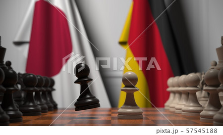 Flags of Japan and Germany behind chess board. The first pawn moves in the beginning of the game Flags of Japan and Germany behind chess board. The first pawn moves in the beginning of the game 57545188