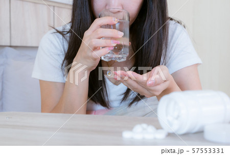 Flu medicine woman Infected With Cold the drug is placed on the table and a glass of water. Flu medicine woman Infected With Cold the drug is placed on the table and a glass of water. 57553331