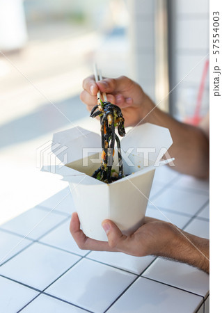 Close-up of man eating chinese noodles in a cafe. The concept of healthy Asian cuisine. Close-up of man eating chinese noodles in a cafe. The concept of healthy Asian cuisine. 57554003