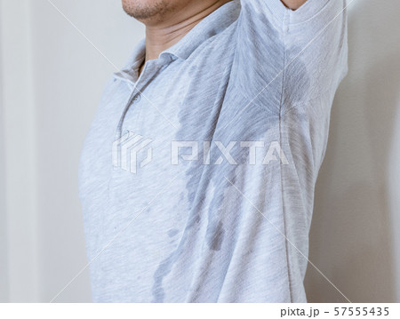 Man with sweat stain on clothes against, using deodorant 57555435