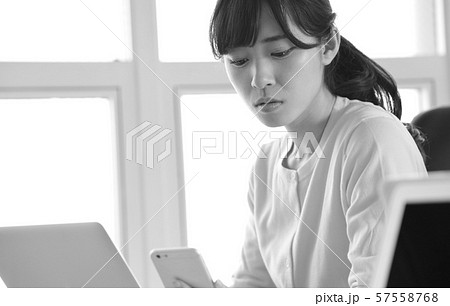 仕事中にスマートフォンを操作する女性イメージ 仕事中にスマートフォンを操作する女性イメージ 57558768