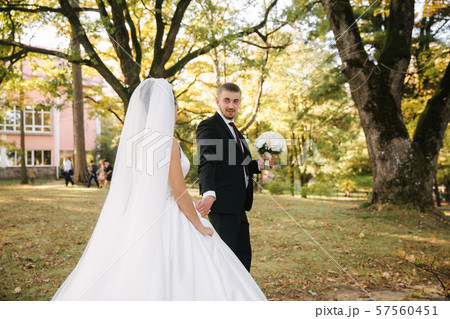 Young bride with groom walking in the forest. Woman with long white dress and man in black suit with 57560451