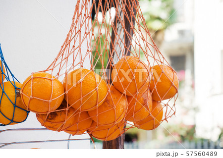 Fresh oranges hang in a mesh bag at the market. Fruit for fresh juice. 57560489