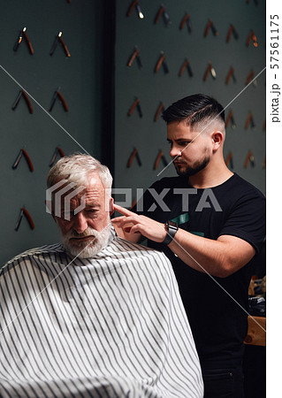 young man trimming old man's hair above ears young man trimming old man's hair above ears 57561175