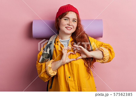 Young cheerful beautiful female tourist smiling in love showing heart with fingers 57562385