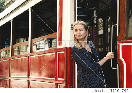 Attractive girl standing in the doorway of red retro tram on the street. Popular sight of Istanbul Attractive girl standing in the doorway of red retro tram on the street. Popular sight of Istanbul 57564746