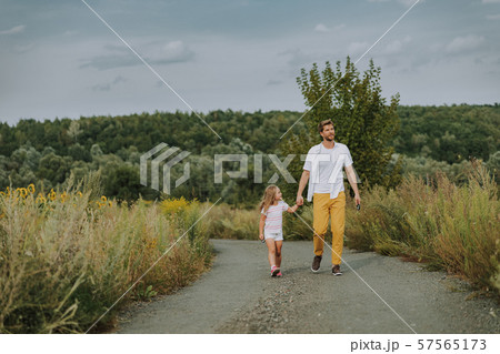 Small Caucasian girl walking with father on road outdoors Small Caucasian girl walking with father on road outdoors 57565173