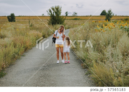 Small Caucasian girl walking with mother on road outdoors Small Caucasian girl walking with mother on road outdoors 57565183