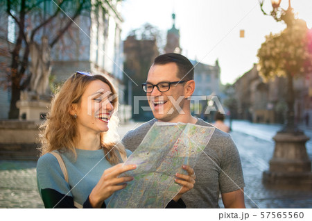 Young happy laughing couple on vacation in European city early in the morning, girl is holding a 57565560