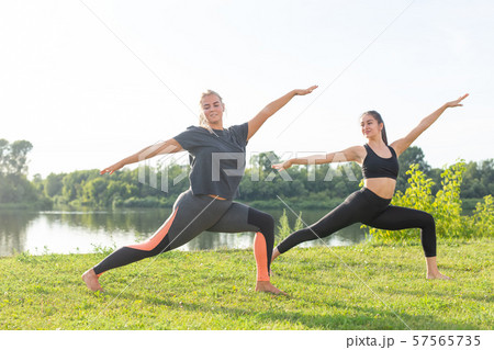 Healthy lifestyle and harmony concept - Young girls doing yoga outdoor 57565735