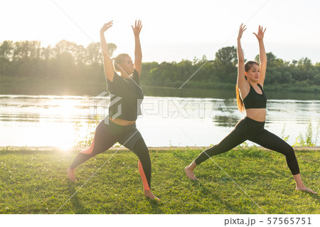 Female friends enjoying relaxing yoga outdoors in the park. Female friends enjoying relaxing yoga outdoors in the park. 57565751