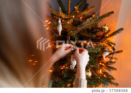 Happy young woman decorating christmas tree at home. Winter holidays in a house interior. Golden and Happy young woman decorating christmas tree at home. Winter holidays in a house interior. Golden and 57568368