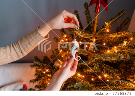 Happy young woman decorating christmas tree at home. Winter holidays in a house interior. Golden and 57568372