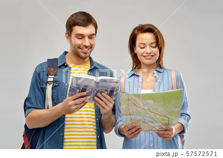 happy couple of tourists with city guide and map happy couple of tourists with city guide and map 57572571