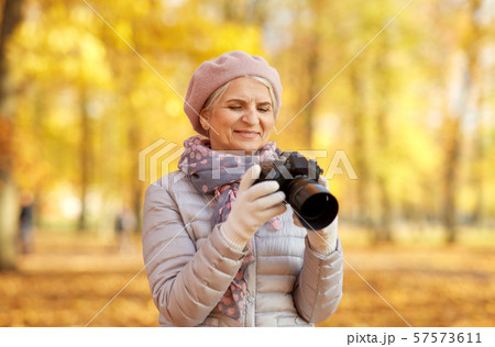 senior woman with photo camera at autumn park 57573611