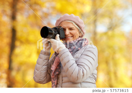 senior woman with photo camera at autumn park 57573615