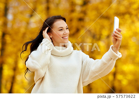 woman taking selfie by smartphone at autumn park 57573622
