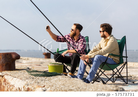 friends fishing and taking selfie by smartphone 57573731