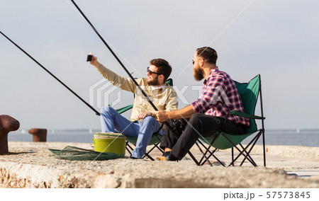 friends fishing and taking selfie by smartphone 57573845