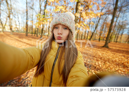 girl taking selfie making duck face at autumn park girl taking selfie making duck face at autumn park 57573928