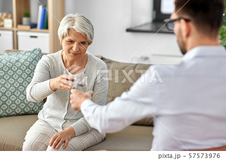 psychologist giving glass of water to senior woman 57573976
