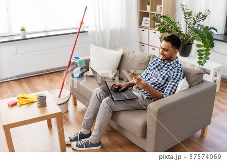man with laptop shopping online after cleaning man with laptop shopping online after cleaning 57574069