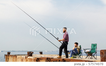 male friends with fishing rods on sea pier male friends with fishing rods on sea pier 57574070
