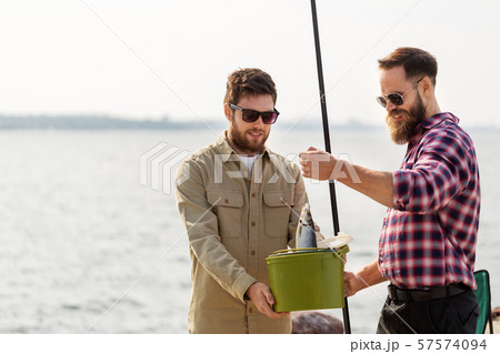 male friends with fish and fishing rods on pier 57574094