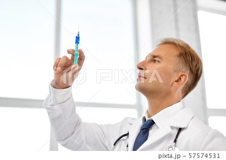 smiling doctor with syringe at hospital smiling doctor with syringe at hospital 57574531