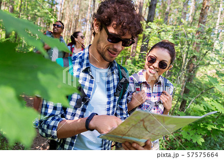 friends with map and backpacks hiking in forest 57575664