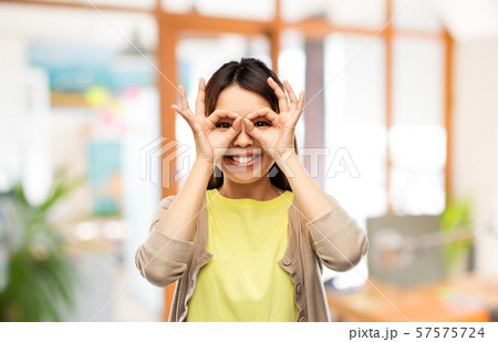 smiling asian woman looking through finger glasses 57575724