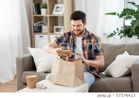 smiling man unpacking takeaway food at home smiling man unpacking takeaway food at home 57576413