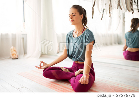 woman meditating in lotus pose at yoga studio 57576779