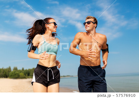 couple with phones and arm bands running on beach couple with phones and arm bands running on beach 57576910