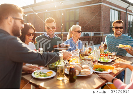 happy friends eating at barbecue party on rooftop happy friends eating at barbecue party on rooftop 57576914